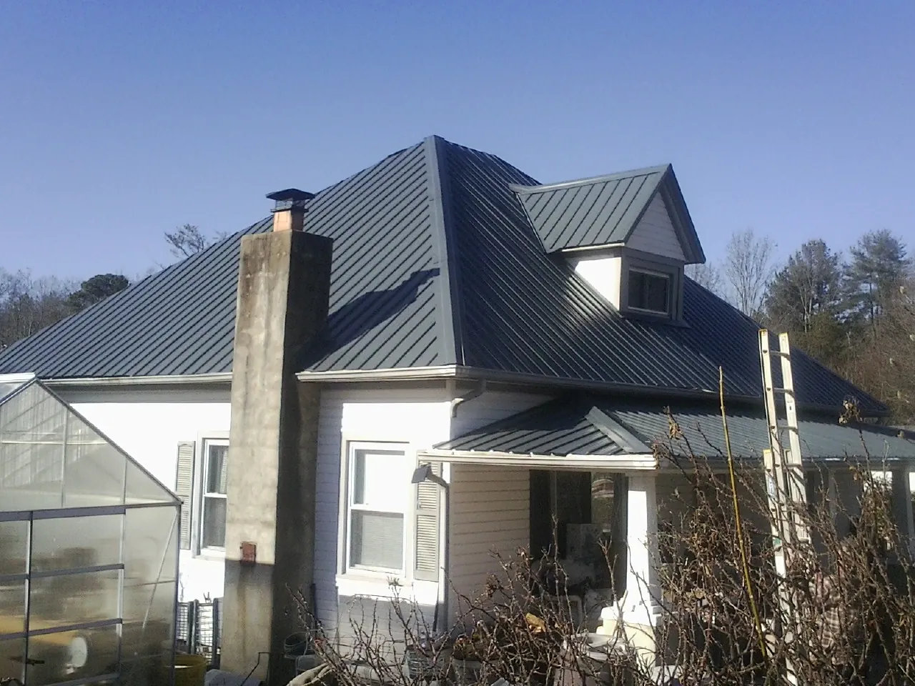 Dark blue standing seam metal roof on a white farmhouse with dormer — Slate & Tile Roof Repair by Roofing Brothers in Port Trevorton