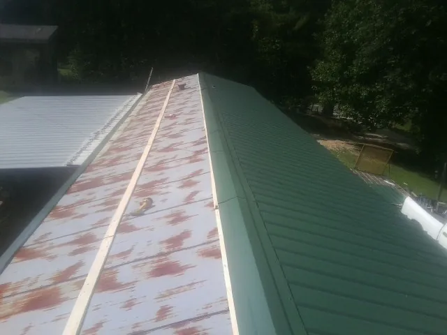 Old rusted panels beside newly installed green metal roofing — Wind Damage Roof Repair by Roofing Brothers in Port Trevorton