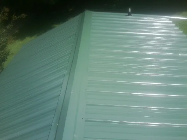 New green metal panels meeting at the ridge of a roof — Flat Roof Repair work by our crew in Port Trevorton