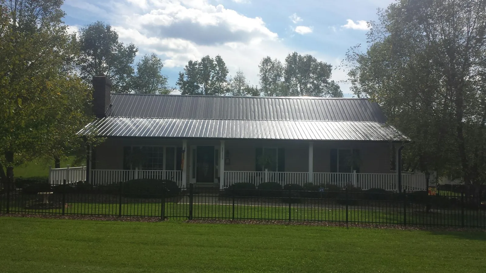 Gray metal roof on a brick ranch with a full width front porch — Gutter Guard Installation work by our crew in Port Trevorton