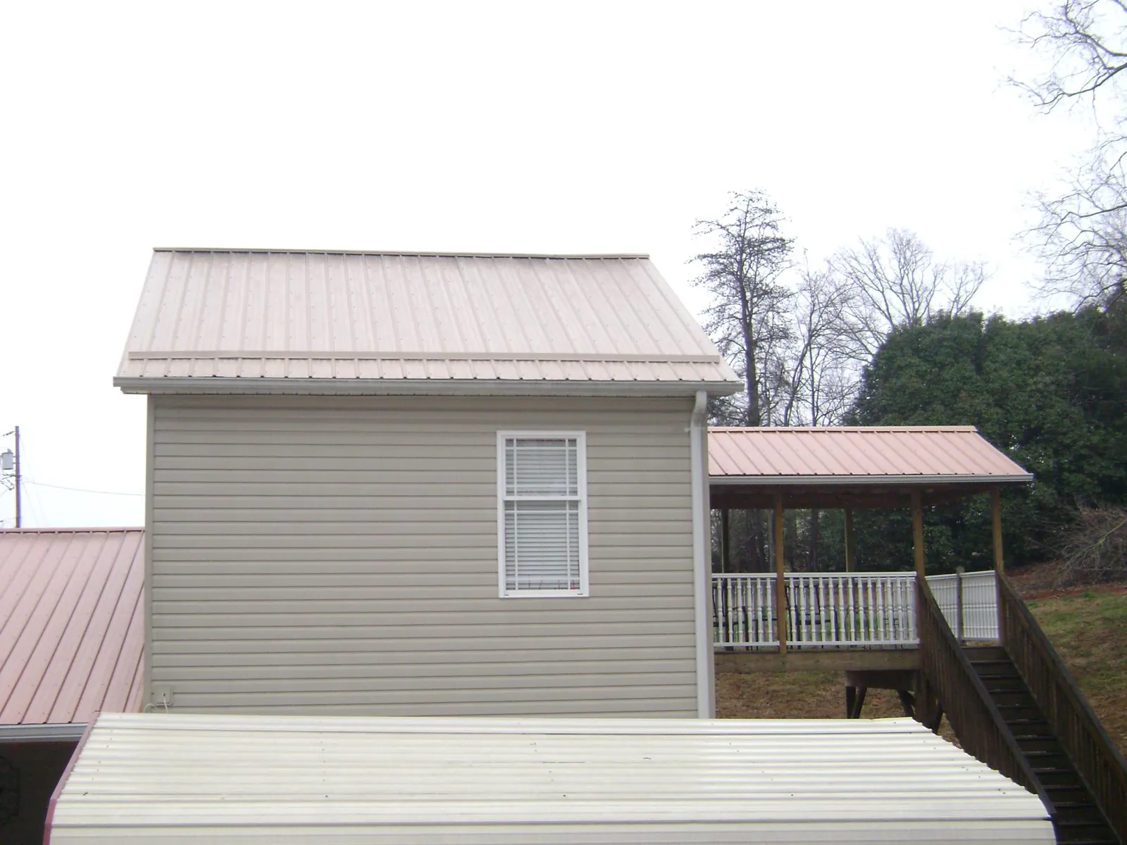 Tan metal roofs on a two story addition and attached porch, from a Roof Replacement job in Port Trevorton